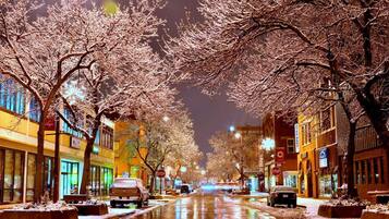 A snow-covered street at night with illuminated buildings and trees.