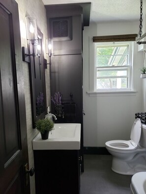 A bathroom with a white sink, a toilet, and a window with blinds.