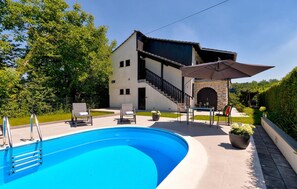 Une maison moderne dotée d’une piscine, d’un espace salon extérieur et d’une arche en pierre.