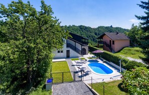 Une maison moderne dotée d’une piscine, d’un patio couvert et d’un escalier en pierre menant à un balcon.