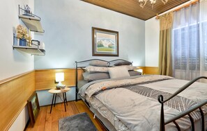 Une chambre à coucher avec un lit, une table de chevet, une lampe et un tableau encadré au mur.