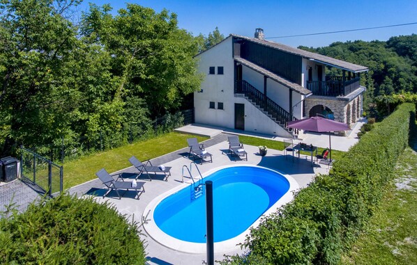 Une maison moderne à deux étages, dotée d’une piscine, d’un espace salon extérieur et d’un escalier en pierre.