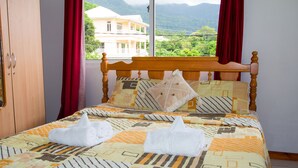 A bed with a patterned bedspread, two towels, and a wooden headboard.