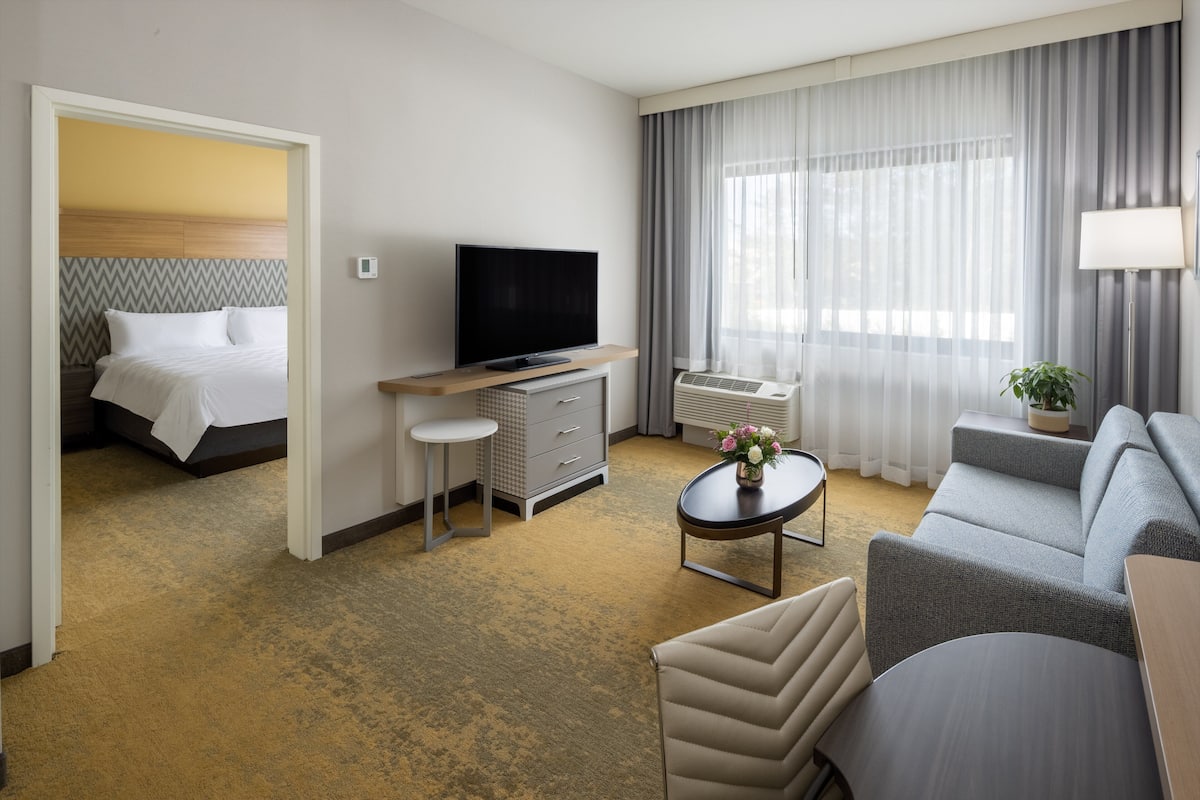 Een hotelkamer met een bed, televisie, bank, salontafel en bureau.