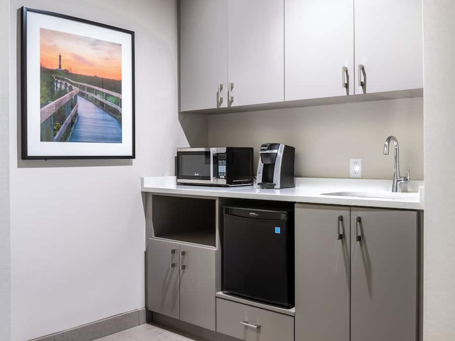 A compact kitchenette with a microwave, coffee maker, and dishwasher.