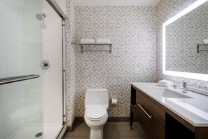 Een moderne badkamer met toilet, douche en een wastafel met spiegel.