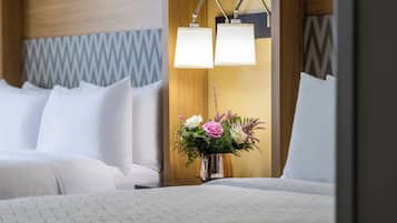 Et hotelværelse med en seng, to sengeborde med lamper og en blomsterdekoration på et af sengebordene.