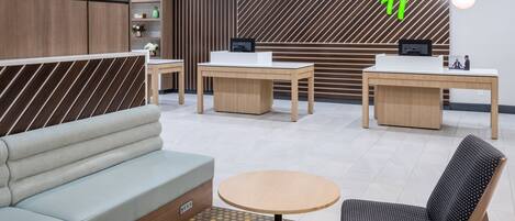 A modern hotel lobby with a reception desk, seating area, and decorative elements.