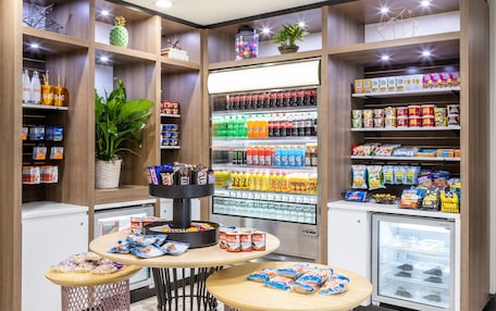 A well-organized snack and beverage section with shelves stocked with various products, a refrigerated display, and a small table with snacks.