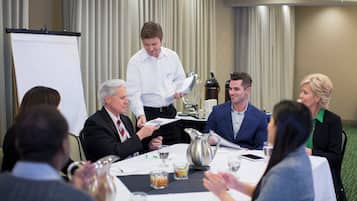 A conference room with a whiteboard, a projector, and a table set for a meeting.