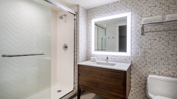 Une salle de bain moderne avec une douche à parois de verre, un meuble-lavabo en bois et des toilettes.