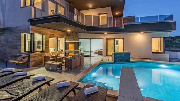Una casa moderna con piscina, zona de estar exterior y barra.