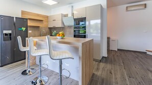 Una cocina moderna con una isla central, taburetes de bar, horno empotrado y refrigerador.