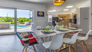 Comedor con vista a la piscina, cocina moderna y mobiliario exterior.