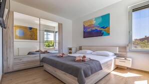 Un dormitorio moderno con una cama grande, un espejo y un cuadro.