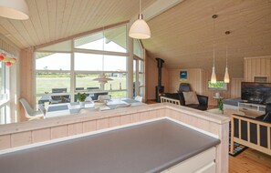 A spacious room with a large window, a fireplace, a dining area, and a TV. - Gorgeous home in Væggerløse with sauna (Væggerløse)