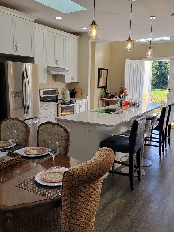 A modern kitchen with white cabinetry, a stainless steel refrigerator, a built-in oven, and a large island with bar seating.