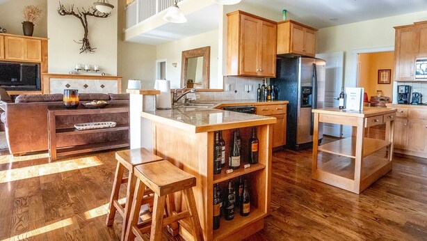 A spacious kitchen with wooden cabinets, a central island, and a built-in wine rack.