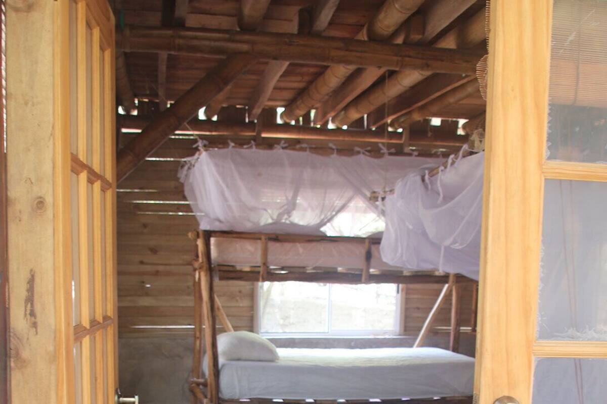 A rustic wooden room with a bunk bed, a small table, and a colorful rug.