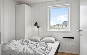Una camera da letto con un letto, una finestra, una lampada a parete e una porta.