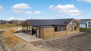 Una casa moderna con tetto spiovente, ampie finestre e un terrazza in legno.