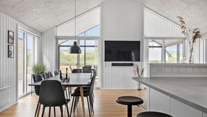 Una cucina moderna con una grande isola, zona pranzo con sedie e TV a parete.