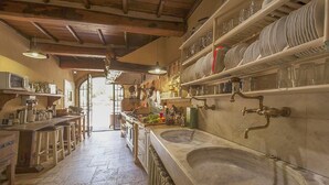 A rustic kitchen with stone countertops, hanging pots, and a large sink. - Cozy home in Greve in Chianti with sauna (Greve in Chianti)