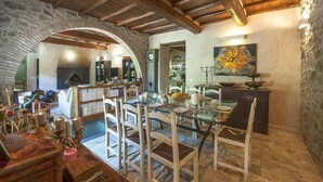 A rustic dining area with a stone archway, wooden beams, and a dining table set for four. - Cozy home in Greve in Chianti with sauna (Greve in Chianti)