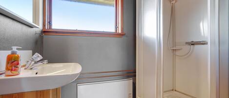A bathroom with a white sink, wooden cabinet, and a glass shower enclosure.