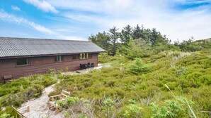 A rustic cabin with a metal roof, surrounded by dense greenery and trees.
