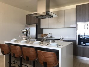 A modern kitchen with a central island, bar stools, and stainless steel appliances. - Andre's Place Condo w stunning view (Cabo San Lucas)