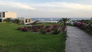 Un hôtel situé sur la côte, doté d’une pelouse verdoyante, d’un chemin en béton et offrant une vue sur la mer.