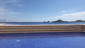 Une piscine offrant une vue sur l’océan et les montagnes lointaines.