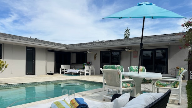 Un espace aménagé au bord de la piscine, avec des chaises longues, une table et un parasol.