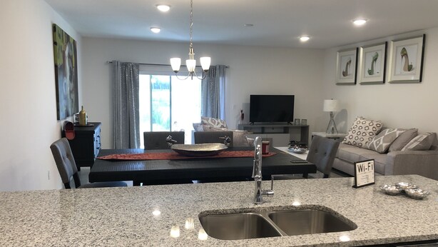 A modern kitchen with granite countertops, stainless steel appliances, and a central island with a sink. - It’s only 15 minutes drive to Disney World and the amazing outlets in Orlando (Kissimmee)
