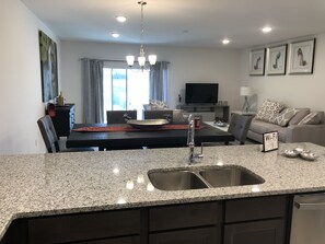 Cocina moderna con encimeras de granito, electrodomésticos de acero inoxidable y una isla central con un lavabo.