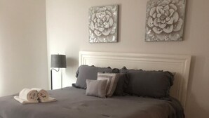 A bedroom with a large bed, a bedside lamp, and two wall art pieces. - It’s only 15 minutes drive to Disney World and the amazing outlets in Orlando (Kissimmee)
