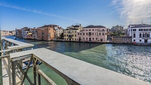 A canal with buildings on either side, a wooden dock, and a clear sky. - Ca' Degli Specchi Grand Canal (Venice)