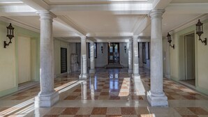 A spacious corridor with marble flooring, white columns, and ornate wall sconces. - Ca' Degli Specchi Grand Canal (Venice)