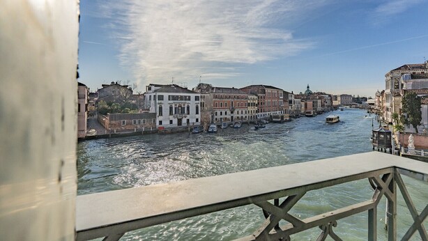 A canal with buildings along the water, a boat, and a clear sky. - Ca' Degli Specchi Grand Canal (Venice)