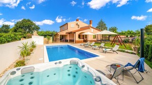 Una casa con piscina, jacuzzi y mobiliario de exterior.