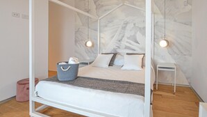 A four-poster bed with a marble wall backdrop, two bedside tables, and a blue woven basket with towels. - Stunning home in Balestrate (Balestrate)