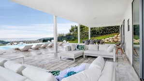 A covered outdoor area with a pool, white lounge chairs, and a sofa with cushions. - Stunning home in Balestrate (Balestrate)