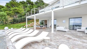 A modern outdoor lounge area with white lounge chairs and a dining setup. - Stunning home in Balestrate (Balestrate)