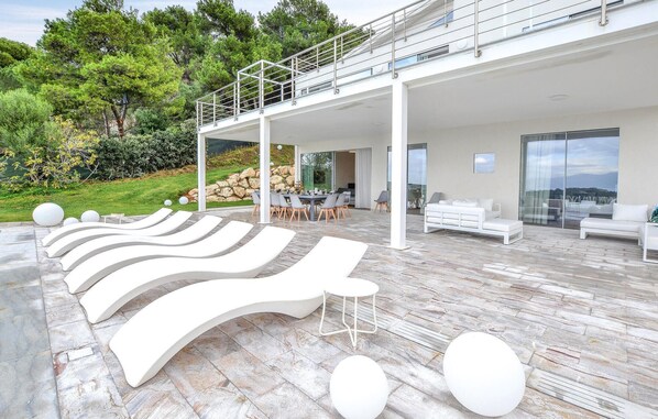 A modern outdoor lounge area with white lounge chairs and a dining setup.