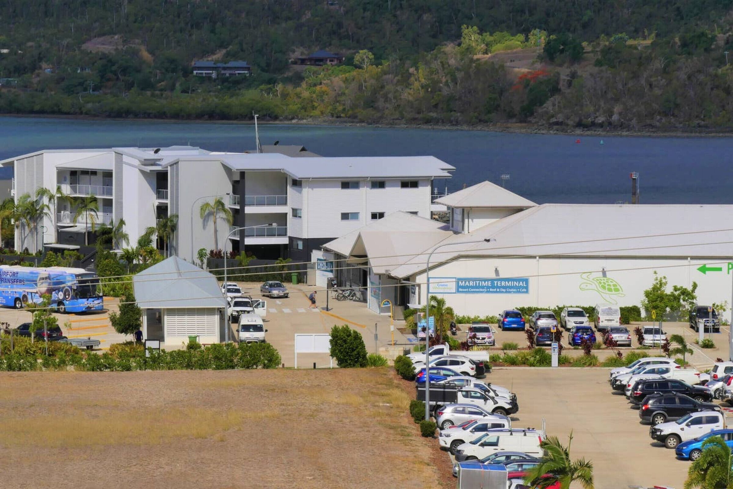 A marina terminal with multiple parking spaces, a covered waiting area, and a view of the water.