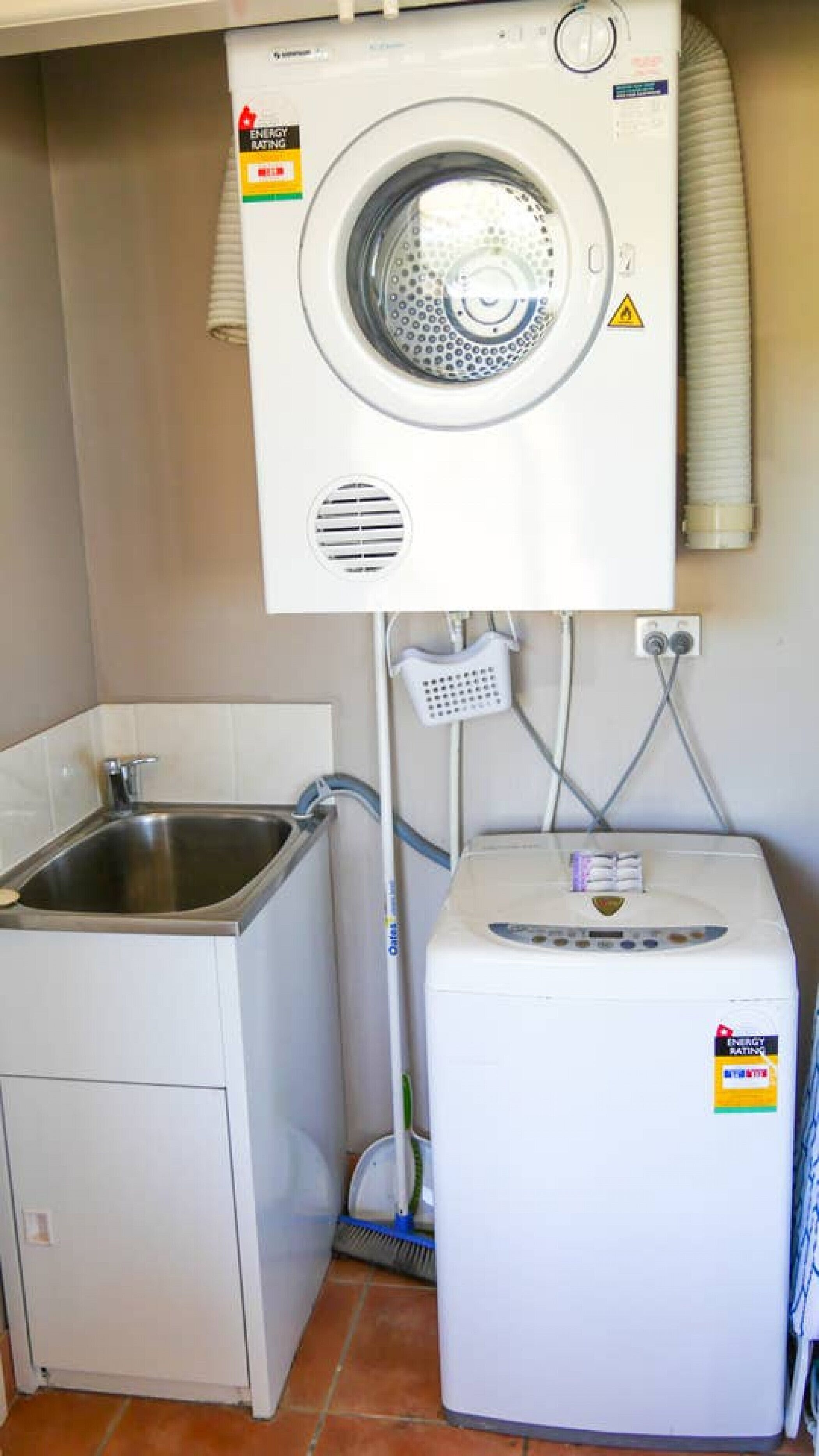 Pequeña lavandería con lavadora, lavabo y secadora.