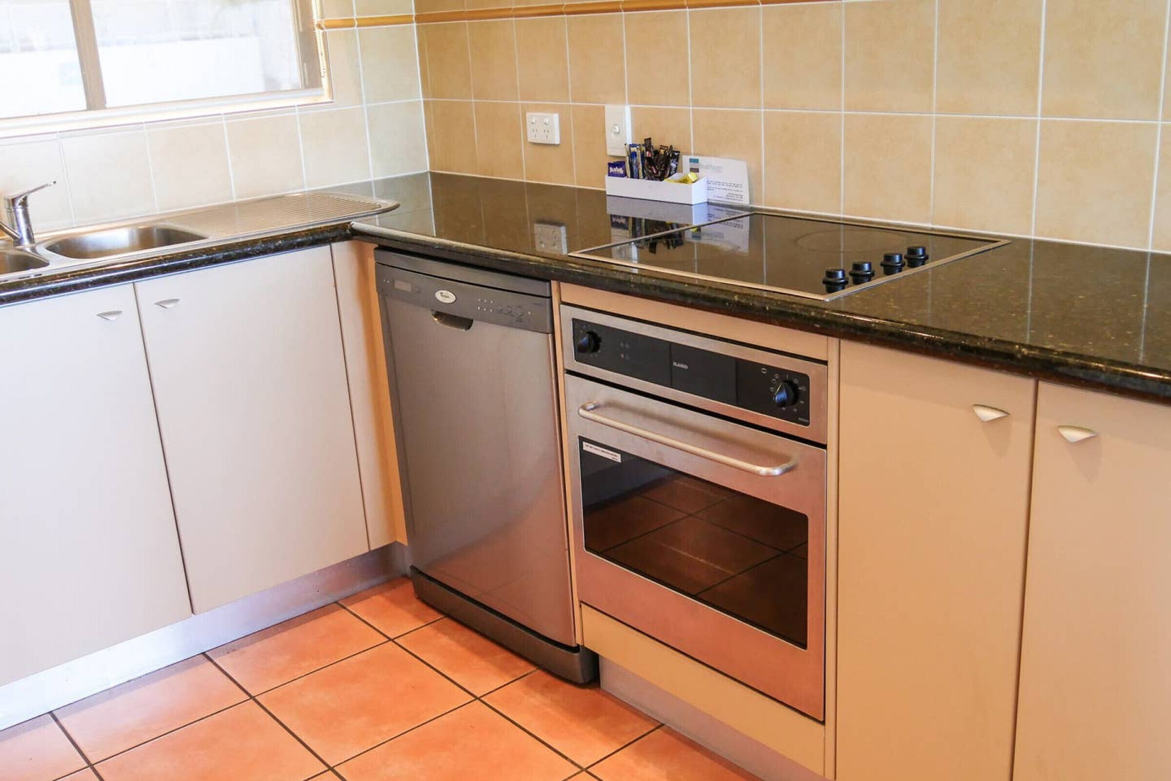 A kitchen with a dishwasher, oven, and a countertop with a sink.