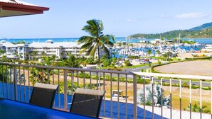 A resort view with a pool, palm trees, and a marina. - Spa Haven Deluxe 17A (Airlie Beach)