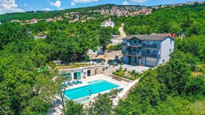 A multi-story building with a swimming pool and outdoor seating, surrounded by lush greenery and a hilly backdrop. - Gorgeous home in Imotski (Imotski)